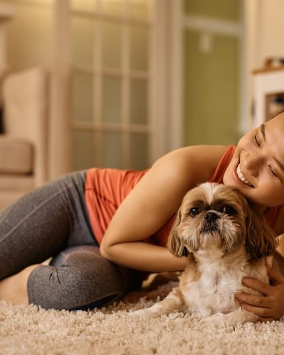 Happy Asian sportswoman enjoying with her dog after home workout.