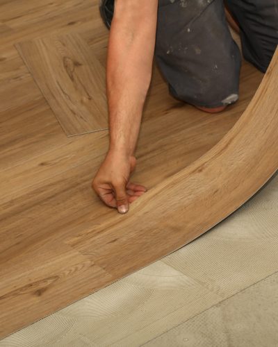 A worker installing new parquet vinyl tiles on floor